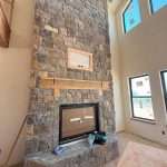 In-House design featuring a tall stone fire place in a custom home by Oak Built Custom Homes