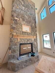 In-House design featuring a tall stone fire place in a custom home by Oak Built Custom Homes