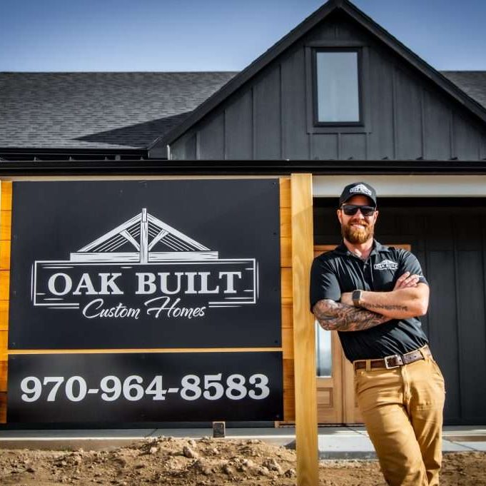 Oak Built Homes Charlie Mezzenga standing next to a sign with their logo and phone number.